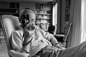 Henri Cartier-Bresson seduto sulla poltrona con l'immancabile macchina fotografica