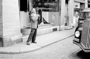 Henri Cartier-Bresson sul marciapiede con in mano la sua macchina fotografica