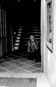Henri Cartier-Bresson accovacciato e seminascosto nell'atrio di uno stabile pronto a cogliere la foto giusta